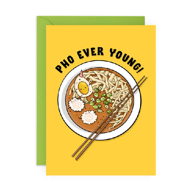 yellow birthday card. top view of a bowl of ramen with narutomaki and a boiled egg wearing a tiny birthday hat. top curved text reads "pho ever young"