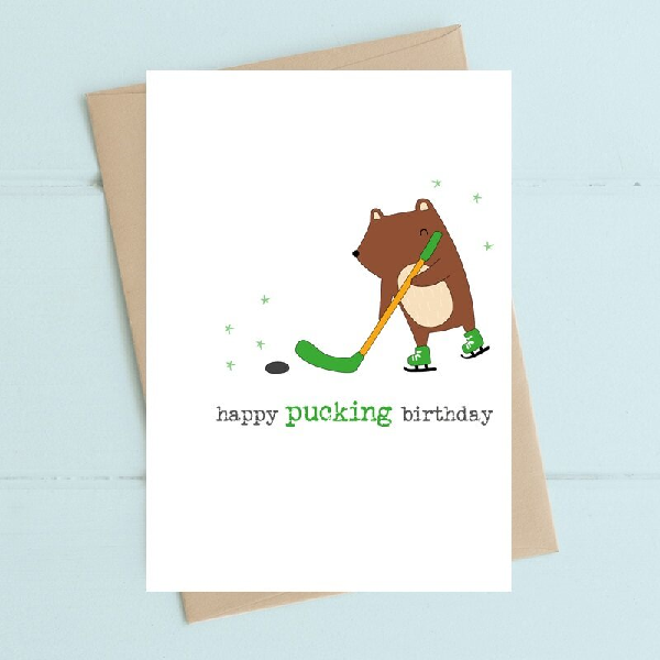 white birthday card with an ambigous rodent playing hockey. text below reads "happy pucking birthday"